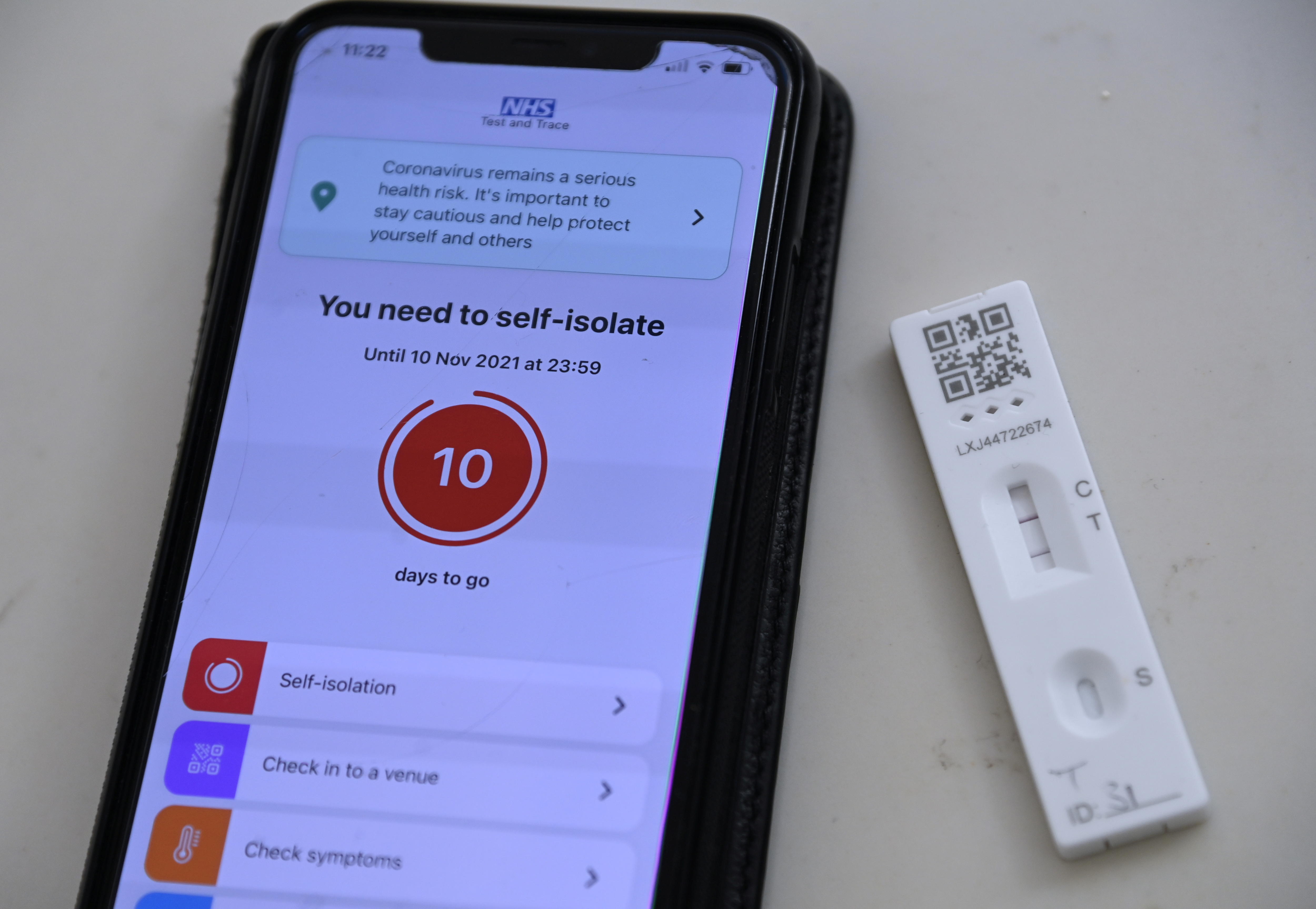A phone screen displays a warning "You need to self-isolate". Next to it is a lateral flow or rapid antigen test with two lines
